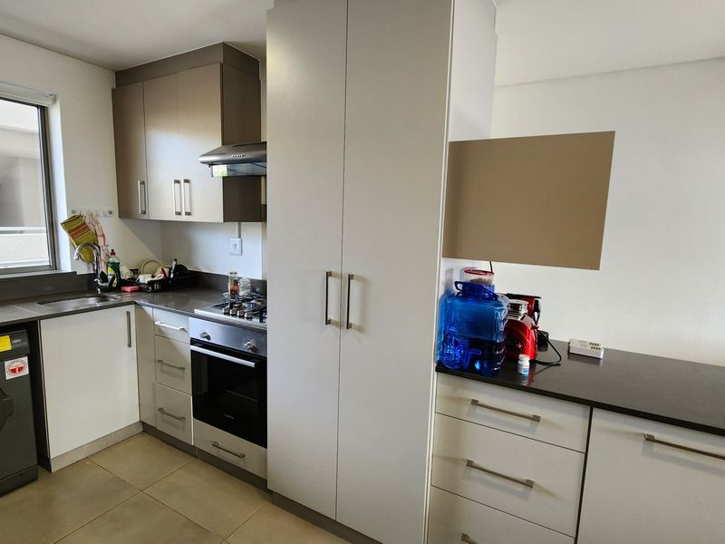 Modern kitchen featuring built-in cabinetry, dark countertops, integrated oven, gas hob, extractor fan, and a built-in laundry appliance.