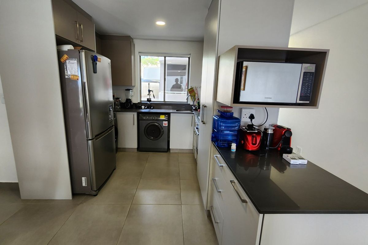 A functional kitchen featuring modern cabinetry, stone countertops, integrated microwave, and tiled flooring, offering a clean and practical workspace.