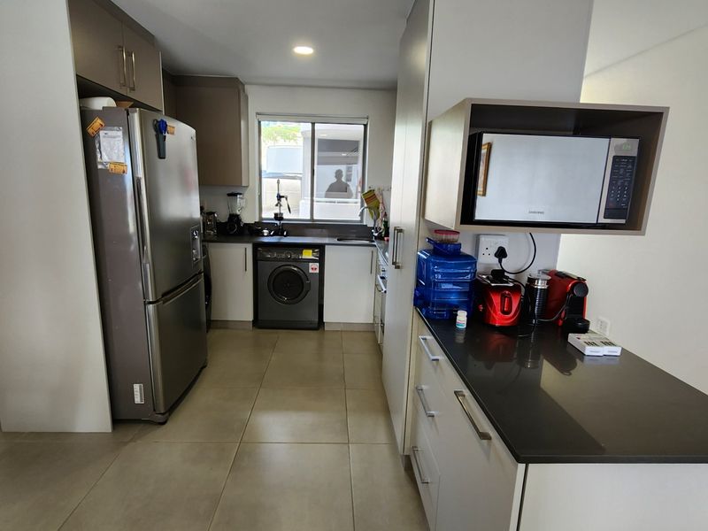 A functional kitchen featuring modern cabinetry, stone countertops, integrated microwave, and tiled flooring, offering a clean and practical workspace.