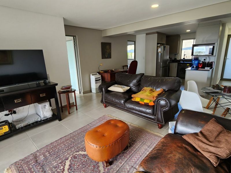 Open-plan living area featuring tiled flooring, recessed lighting, and a functional kitchen with built-in cabinetry and appliances.