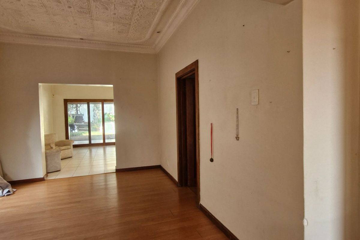 Spacious living area featuring laminate flooring, decorative ceiling details, and sliding glass doors providing access to an adjoining room and outdoor space.