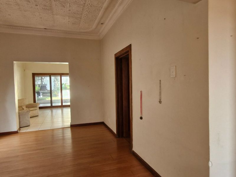 Spacious living area featuring laminate flooring, decorative ceiling details, and sliding glass doors providing access to an adjoining room and outdoor space.