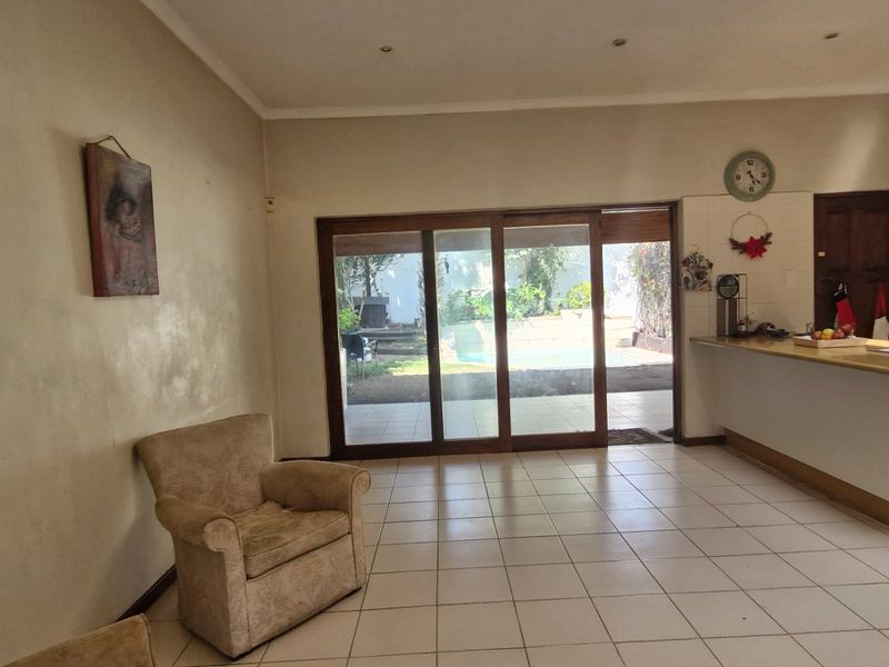 Open-plan living and kitchen area featuring tiled flooring, a breakfast island, and sliding glass doors providing direct access to the outdoor patio and pool area.