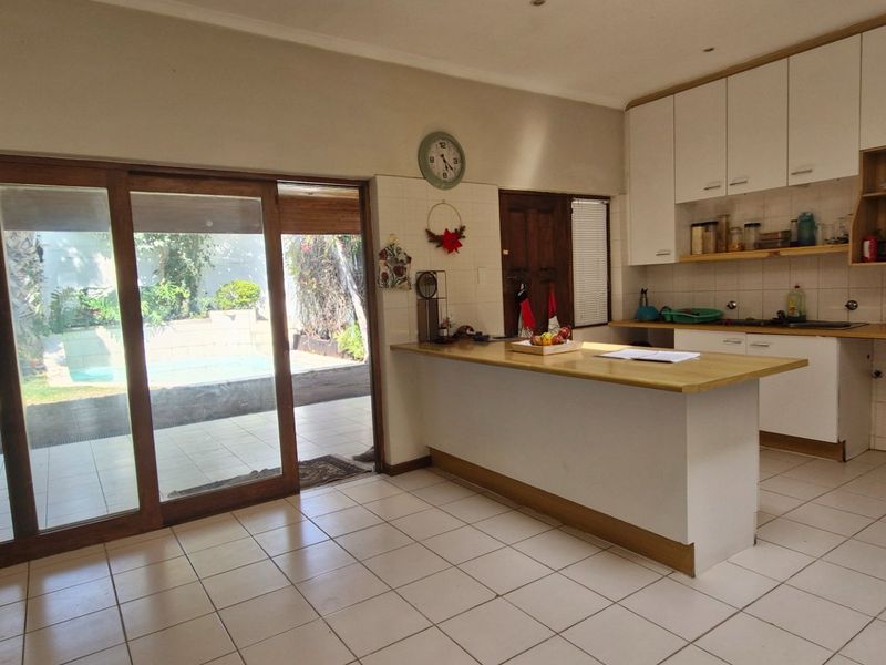 Open plan kitchen area featuring a central island, ample cabinetry, and large sliding glass doors providing direct access to the outdoor patio and pool area.