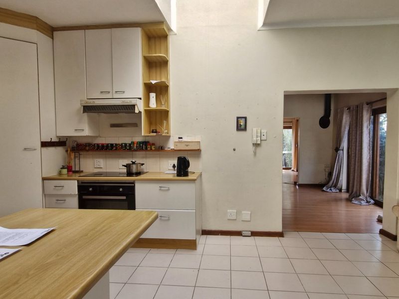A functional kitchen featuring built-in cabinetry, an electric oven and hob, and a central island, with tiled flooring and direct access to the living area.