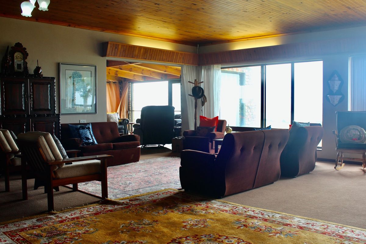 Spacious living room featuring a warm timber-clad ceiling, large sliding glass doors providing natural light, and integrated pelmet lighting.