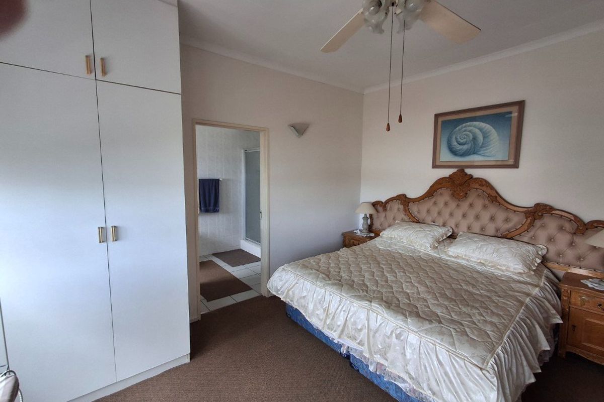 A bedroom featuring built-in cupboards, a ceiling fan, and direct access to an en-suite bathroom.