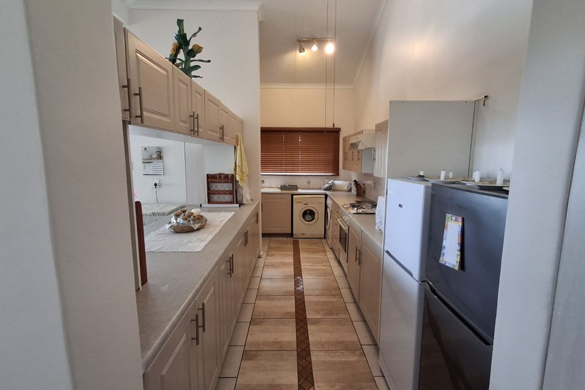 A functional galley-style kitchen featuring ample built-in cabinetry, tiled flooring, and integrated appliances, offering a practical layout for daily use.