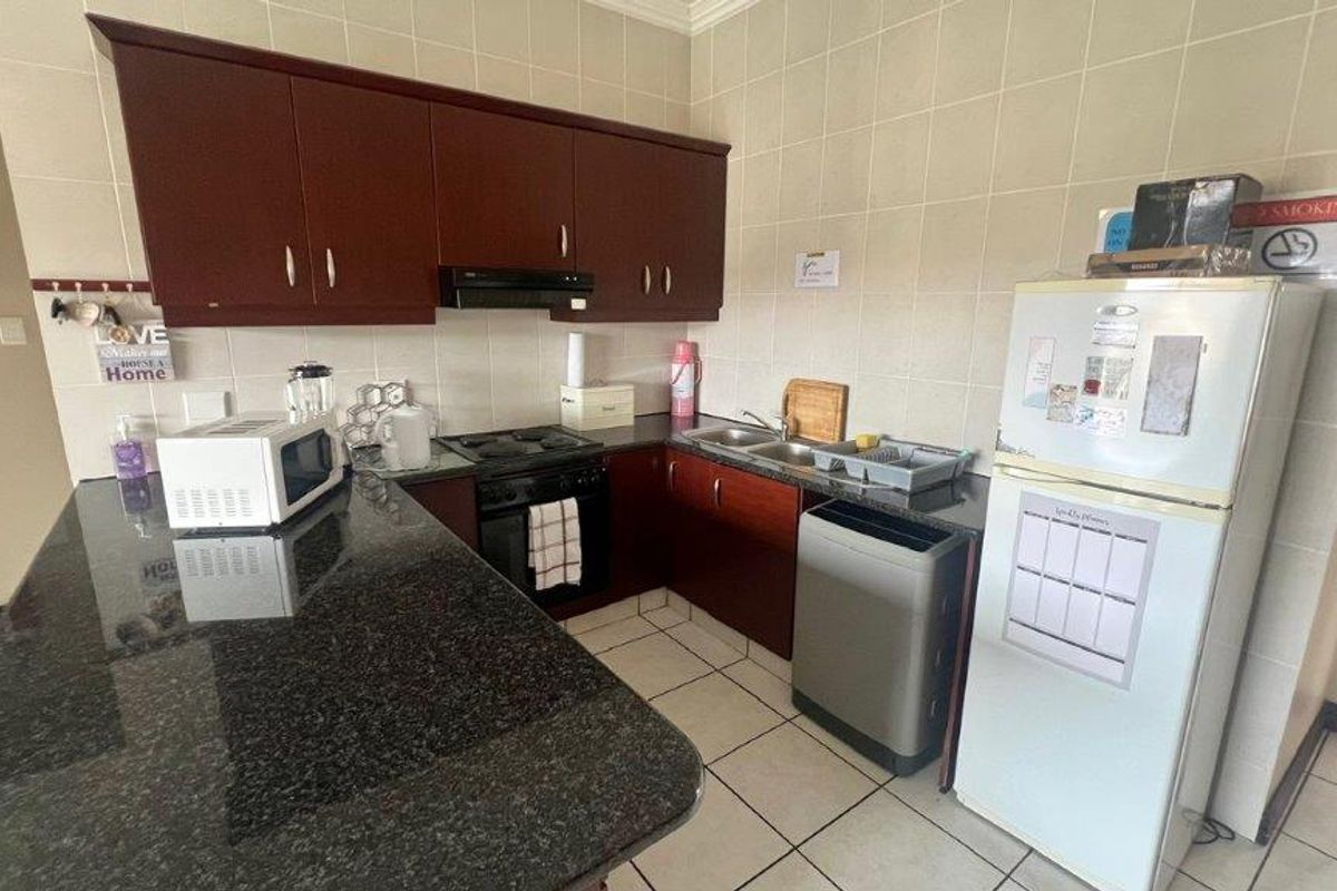 Functional kitchen featuring dark wood cabinetry, granite countertops, tiled splashbacks, and integrated cooking appliances.