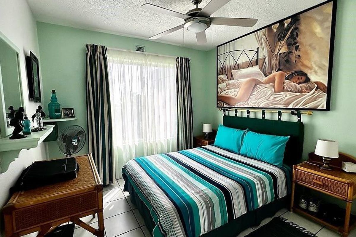 A bedroom featuring a ceiling fan, tiled flooring, and built-in shelving, offering a functional space with natural light.