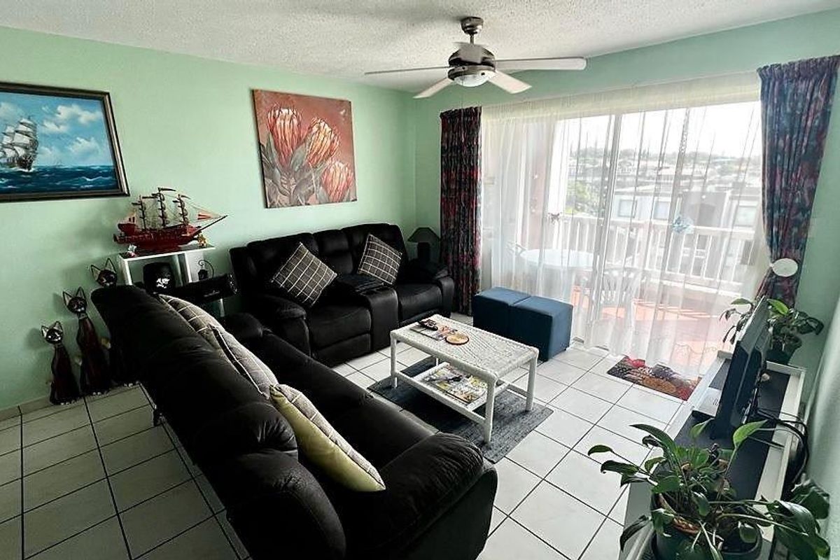 A living room featuring ceramic tile flooring, a ceiling fan, and large sliding glass doors providing access to an outdoor balcony area.