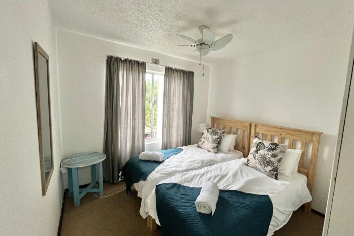 A functional bedroom featuring carpeted flooring, a ceiling fan, and a built-in cupboard, providing a comfortable and practical living space.