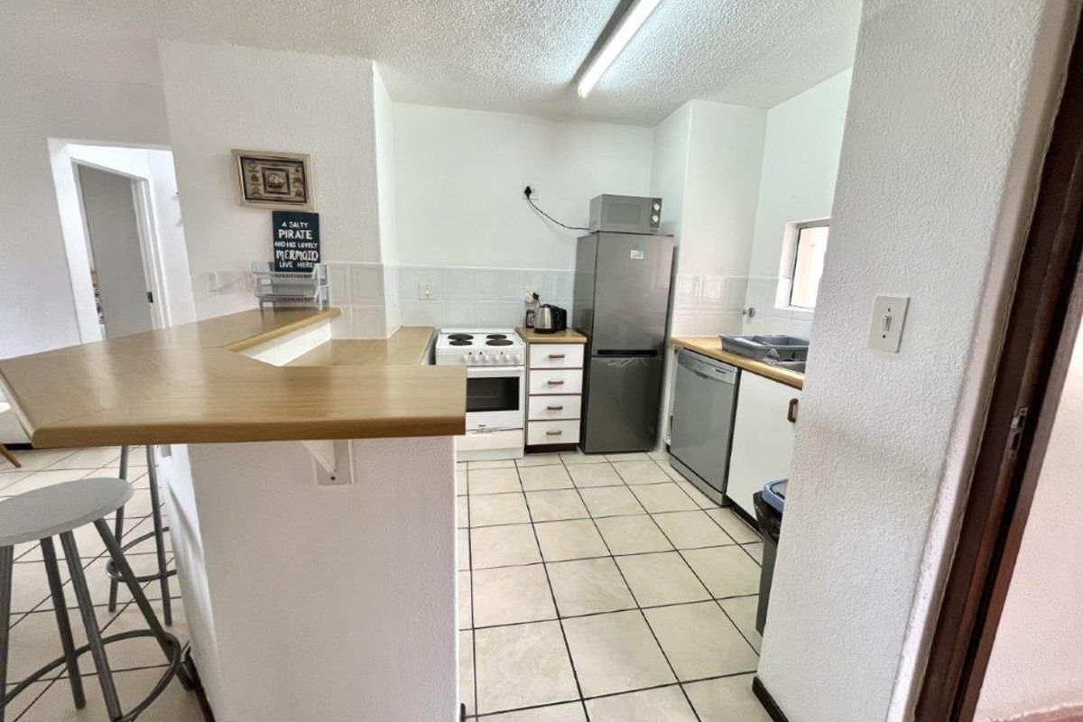 Functional kitchen featuring a breakfast bar, tiled flooring, laminate countertops, and built-in cabinetry with a freestanding stove.