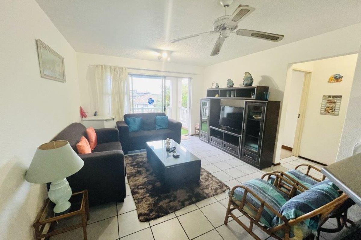 A living room featuring tiled flooring, a ceiling fan, and sliding glass doors that provide access to an outdoor balcony area.