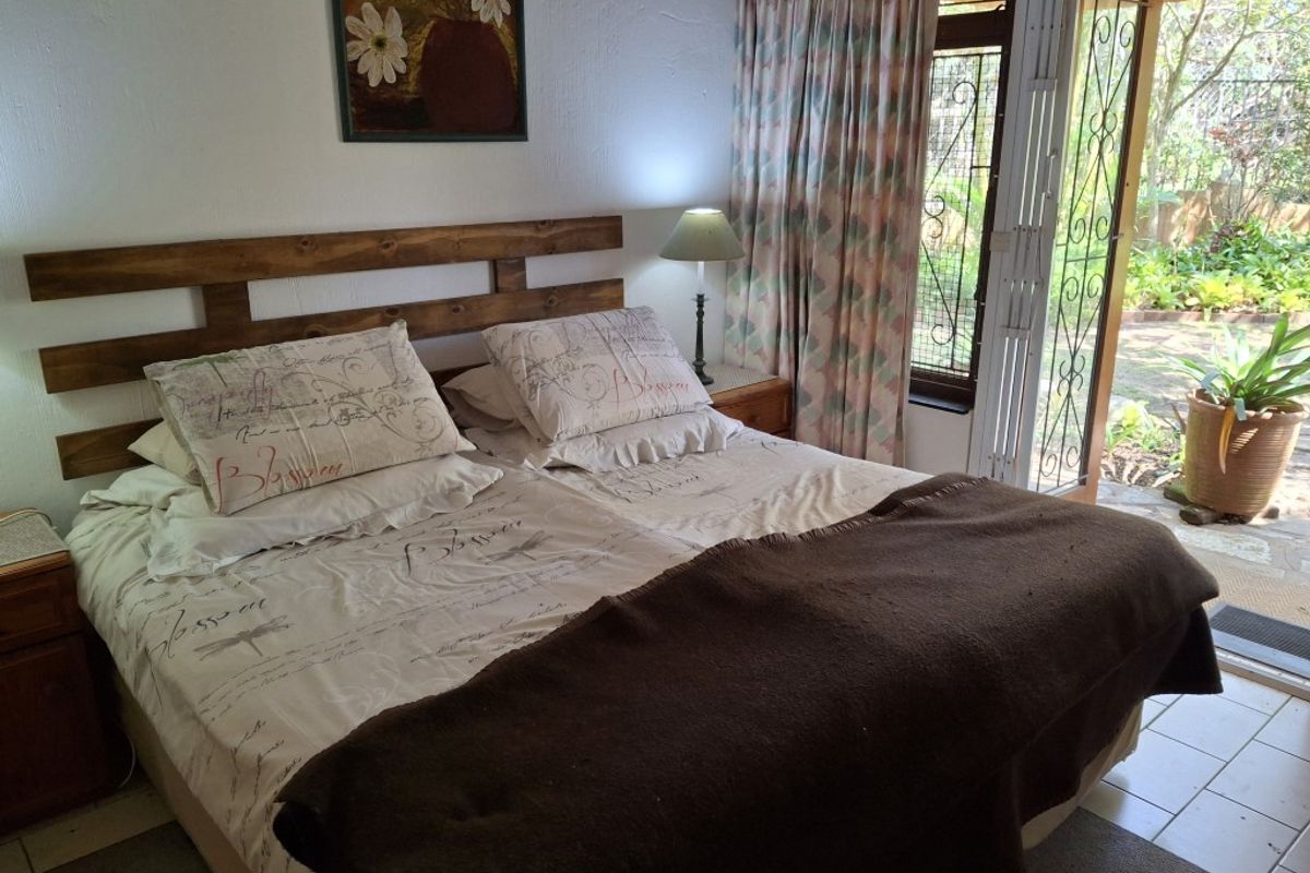 A bedroom featuring tiled flooring and direct access to the garden through a sliding door with a security gate.