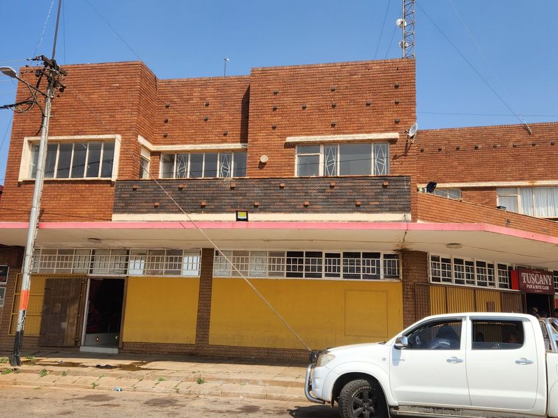 Front elevation of a commercial brick building featuring a covered walkway, metal window frames, and prominent signage for a pub and club.