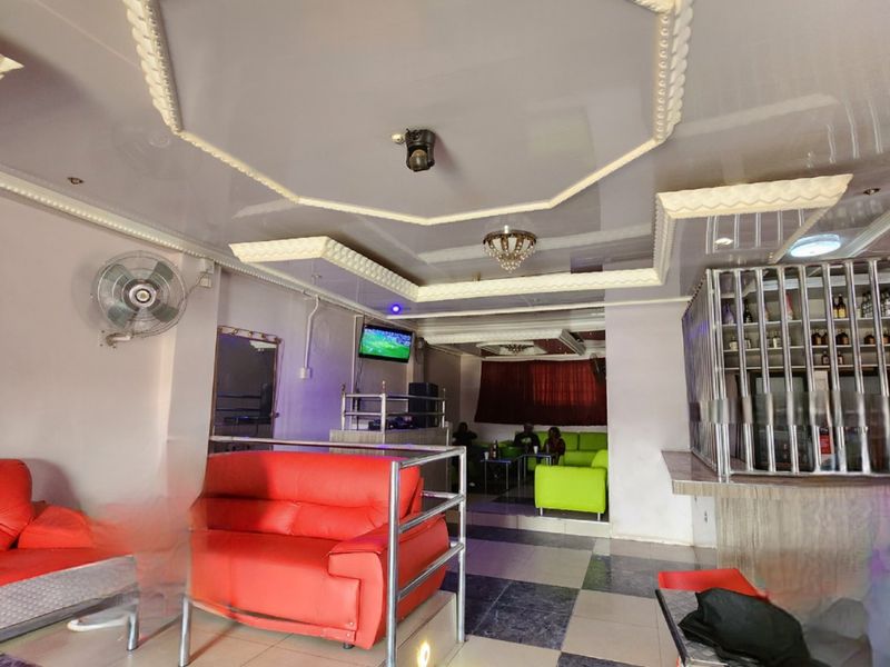 Commercial bar area featuring a built-in service counter, metal security partitioning, and a decorative recessed ceiling design with integrated lighting.