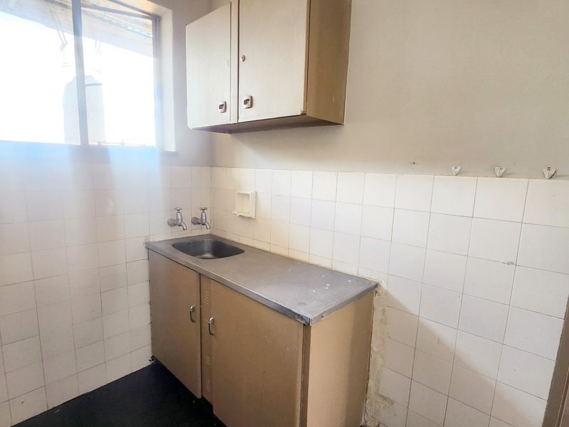 A functional scullery area featuring a stainless steel sink, built-in cabinetry, and tiled splashback, offering a practical space for utility and prep work.