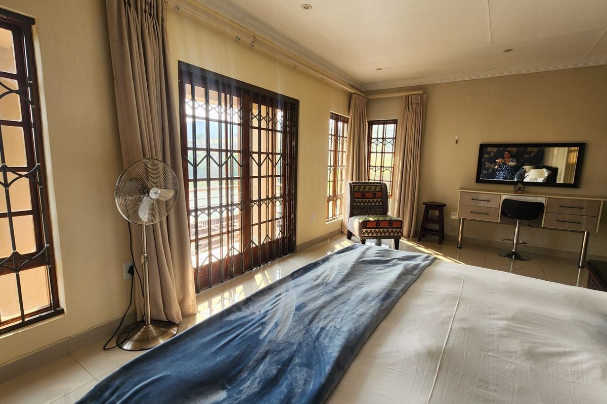 Spacious bedroom featuring tiled flooring, coved ceilings, and sliding glass doors with security gates leading to an outdoor area.
