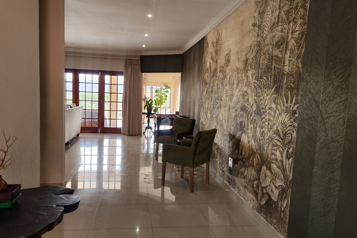 Spacious living area featuring polished tile flooring, decorative feature wallpaper, recessed lighting, and large french doors providing natural light and access to the exterior.