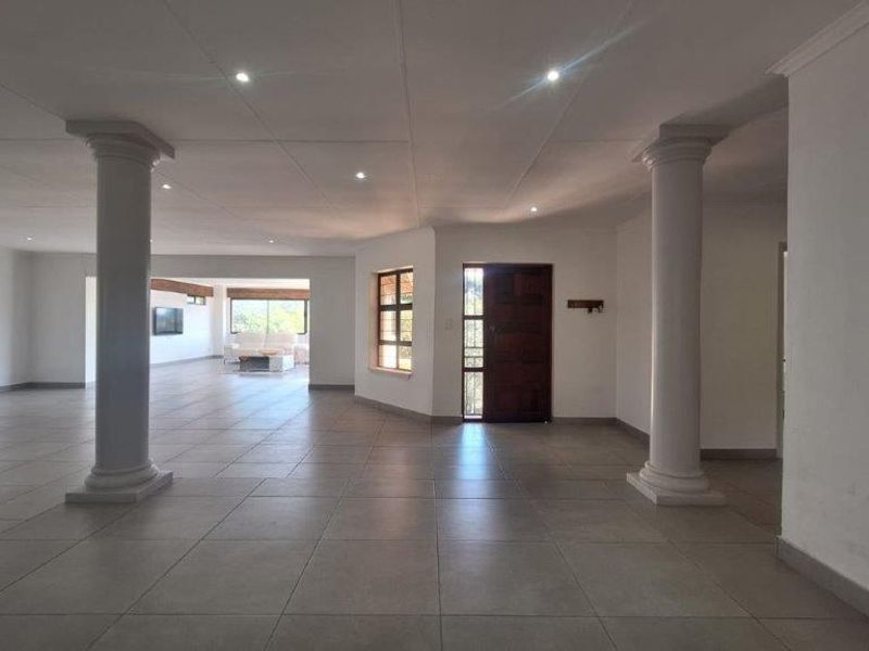 Spacious open-plan living area featuring neutral tiled flooring, decorative columns, and recessed lighting, offering a versatile layout for modern living.