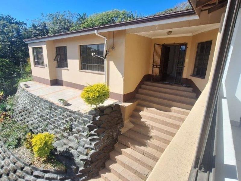 Front entrance of the house featuring a tiled staircase, stone retaining wall, and a covered patio area.