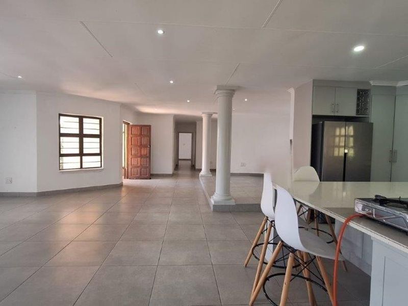 Spacious open-plan living area featuring tiled floors, recessed lighting, structural columns, and a modern kitchen island with built-in cabinetry.