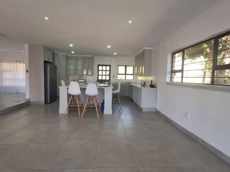 Spacious open-plan kitchen featuring a central island, modern cabinetry, and large windows, seamlessly flowing into the adjacent living area.