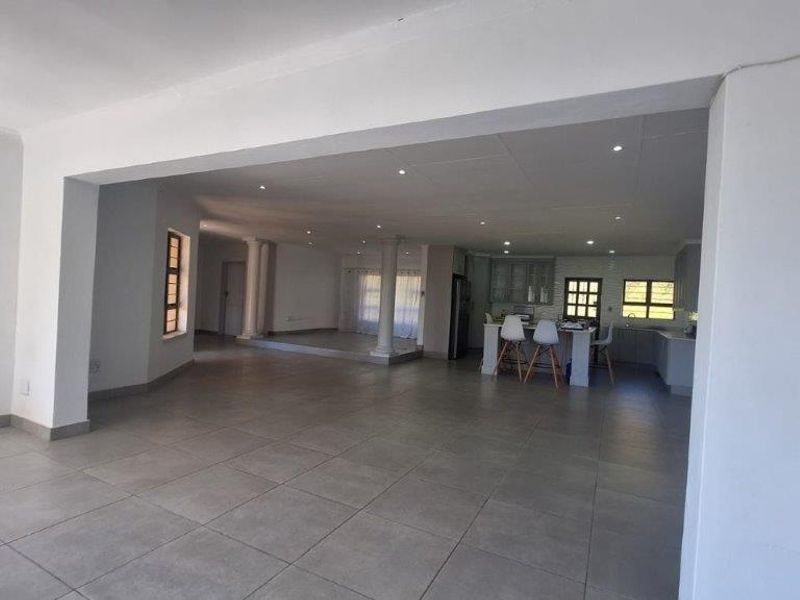 Spacious open-plan living area featuring large format floor tiles, recessed lighting, and a modern kitchen with a central island and built-in cabinetry.