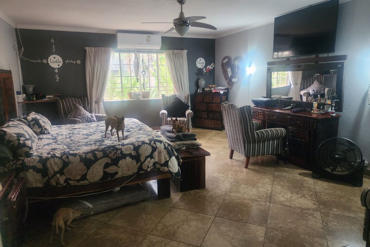 Spacious bedroom featuring tiled flooring, a ceiling fan, and a wall-mounted split-system air conditioning unit.
