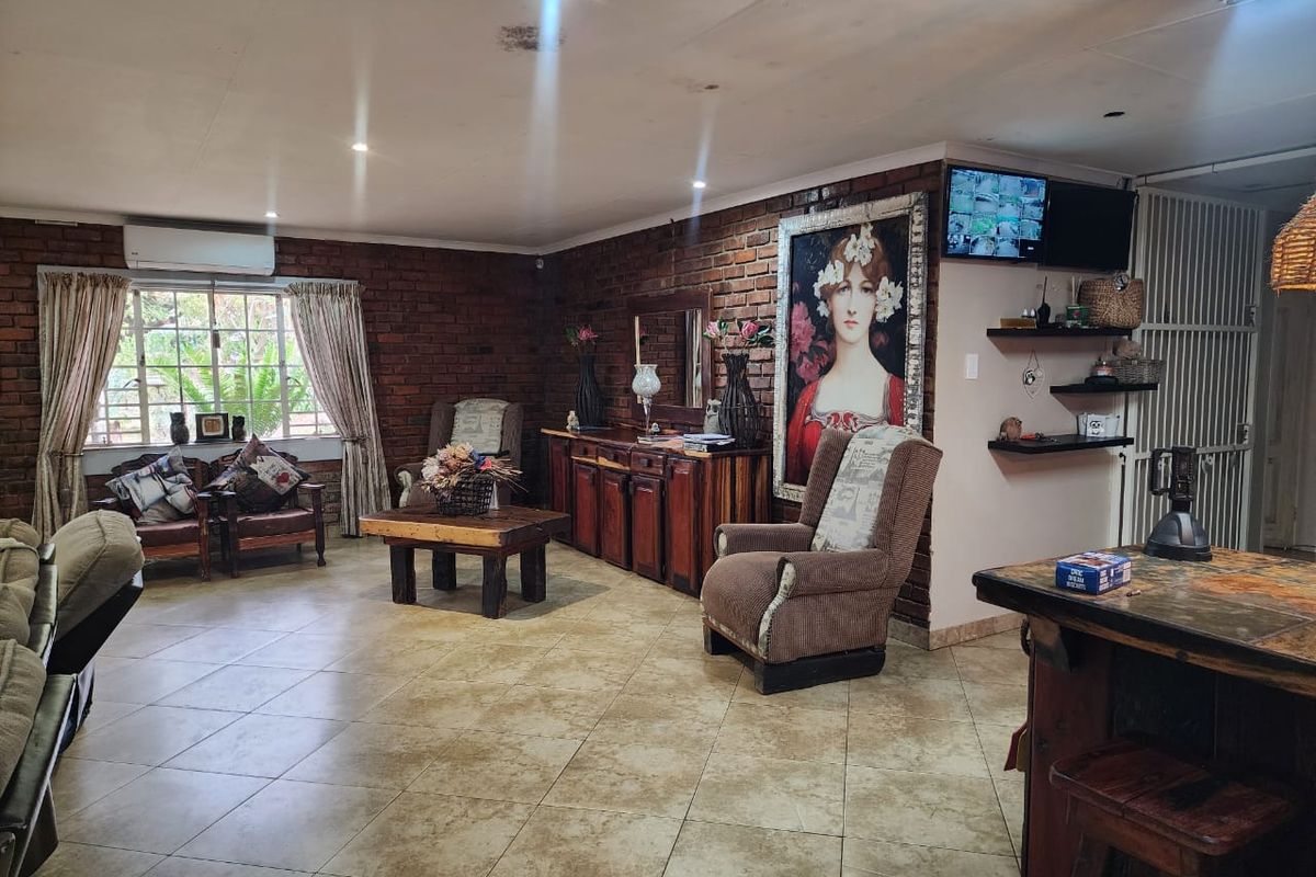 Spacious living area featuring exposed brick walls, ceramic tile flooring, and a split-system air conditioner, with visible ceiling maintenance required.