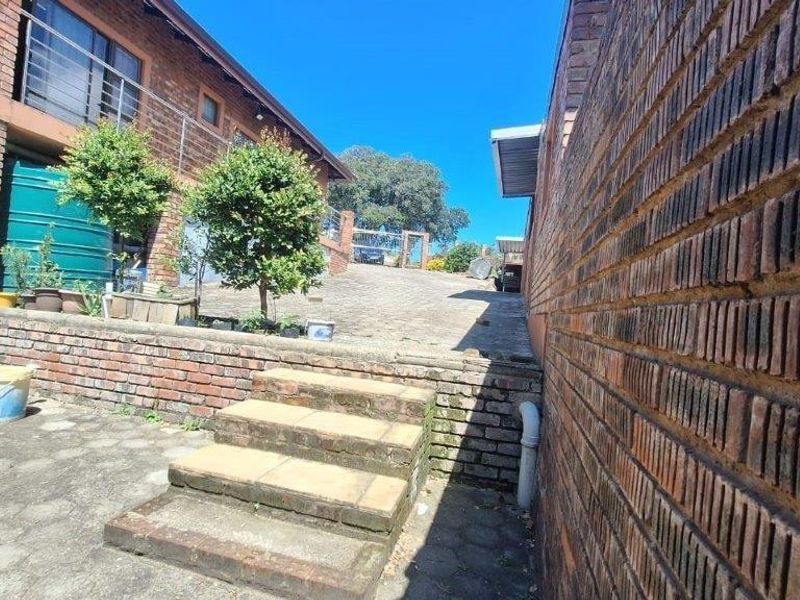 Exterior view of the property side passage featuring brick retaining walls, concrete stairs, and a paved driveway leading to the rear area.