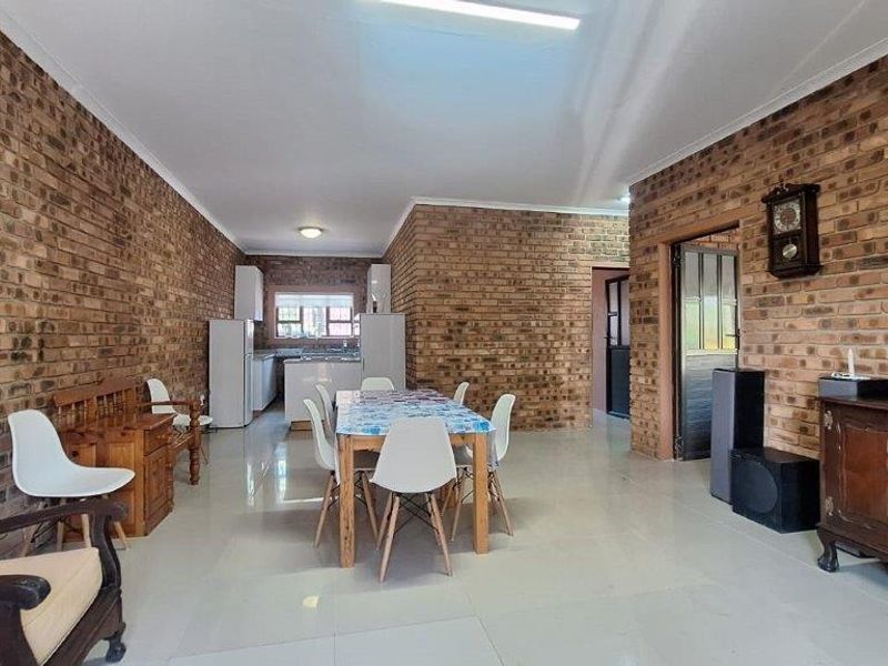Open plan living and dining area featuring exposed brick walls and tiled flooring, seamlessly connected to a functional kitchen space.