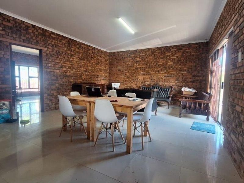 Spacious open-plan living and dining area featuring distinctive face-brick walls and large format floor tiles with direct access to the exterior.