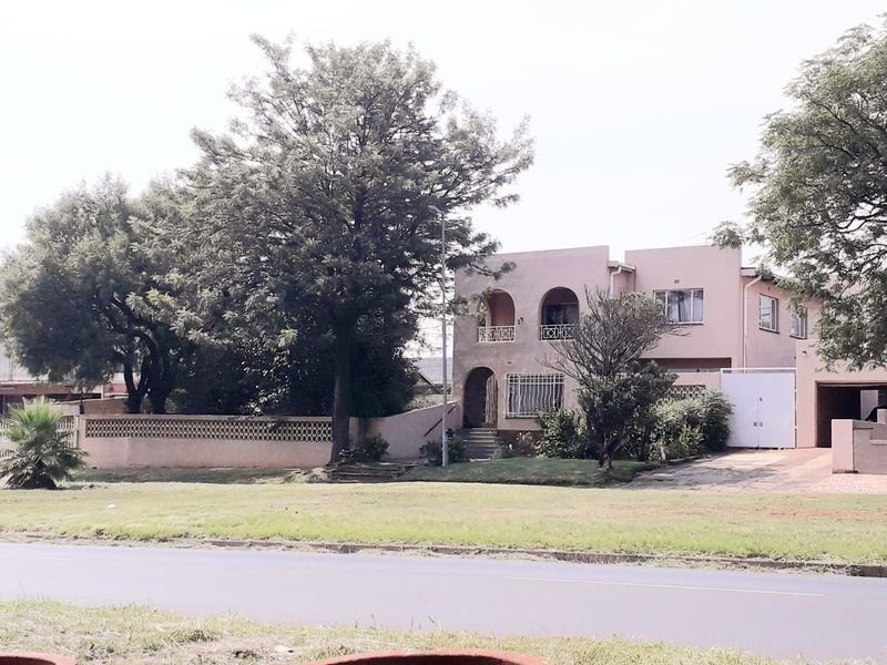 Front exterior view of a two-story commercial property featuring arched architectural details, a perimeter wall, and a paved driveway.