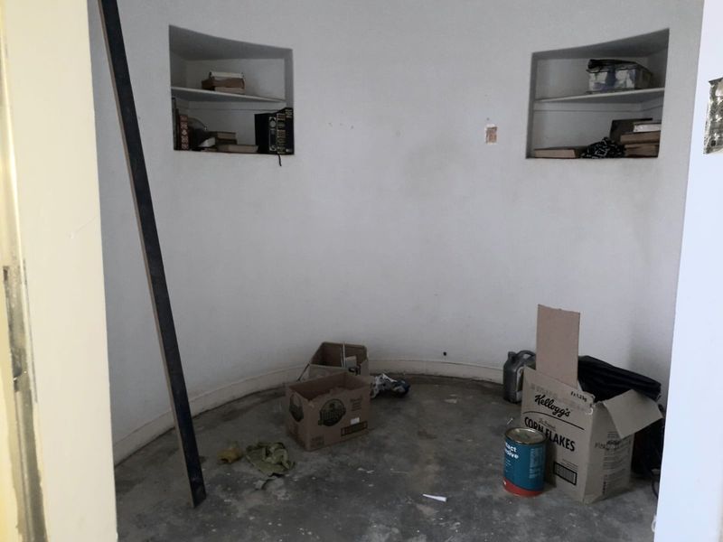 A small, circular-walled utility space featuring two built-in wall niches and unfinished concrete flooring, currently vacant and requiring cosmetic refurbishment.