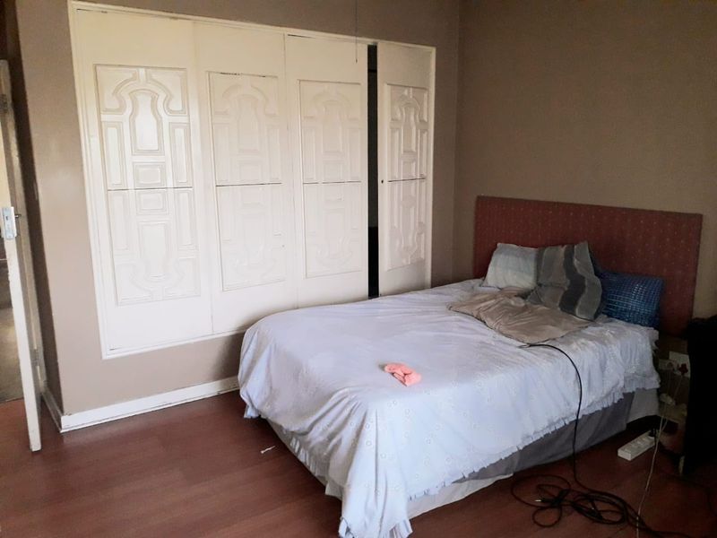 A bedroom featuring laminate flooring and a large built-in wardrobe with decorative panel doors.