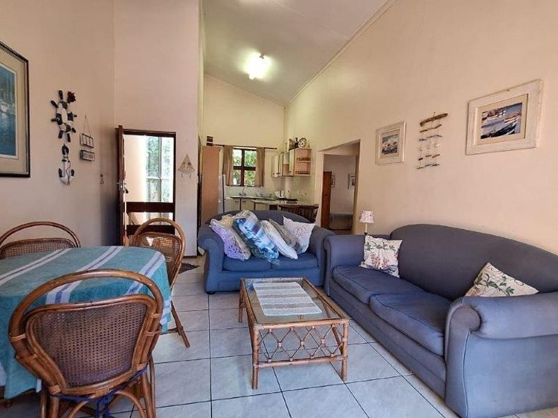 Open-plan living and dining area featuring tiled flooring and a vaulted ceiling, with a view through to the kitchen space.