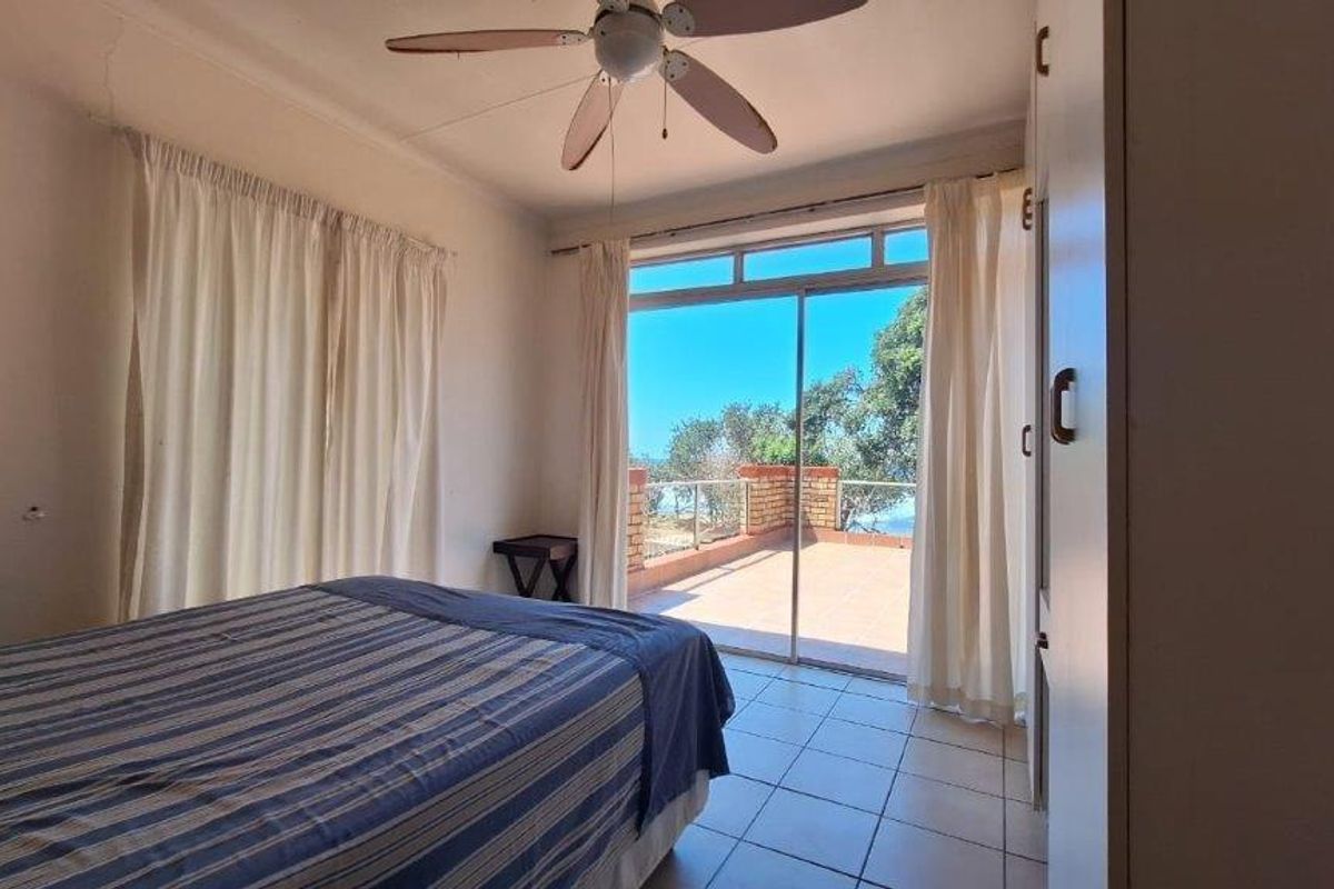 Bedroom featuring tiled flooring, a ceiling fan, built-in wardrobe, and sliding glass doors opening onto a private balcony with scenic views.