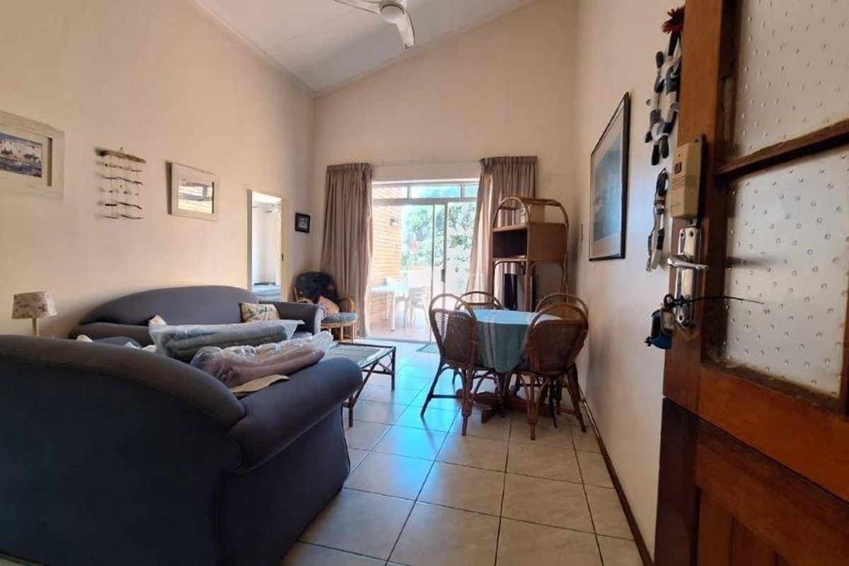 A living room featuring tiled flooring, a vaulted ceiling, and a sliding glass door providing access to an outdoor patio area.
