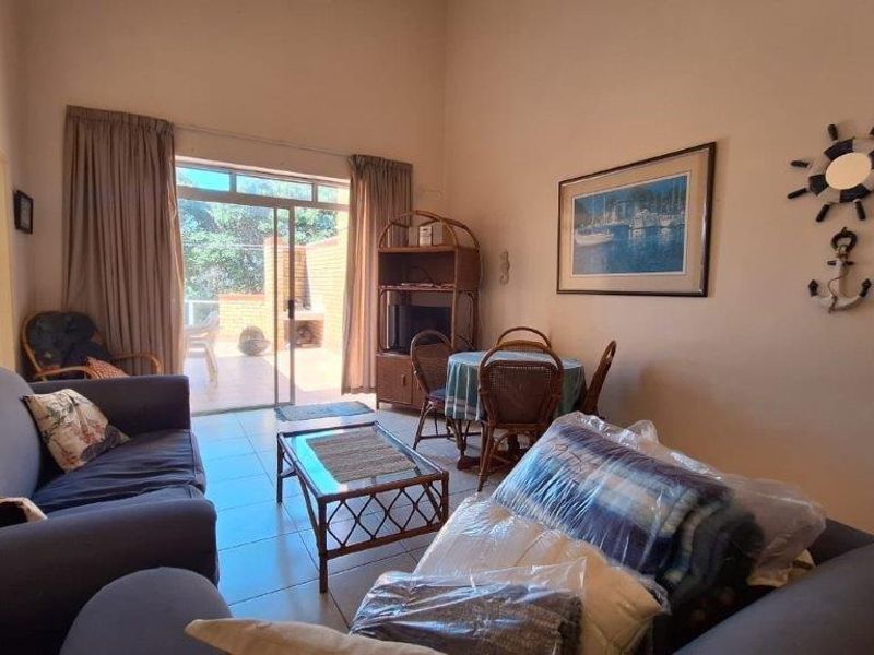 A living room featuring tiled flooring and a sliding glass door providing access to an outdoor patio area.