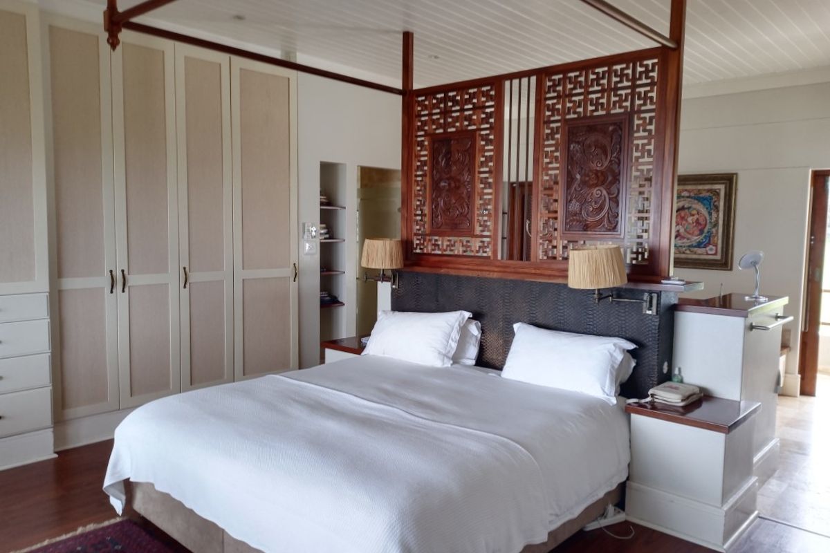 Spacious bedroom featuring extensive built-in cabinetry, a decorative wooden room divider, and timber flooring, creating a warm and well-maintained living space.