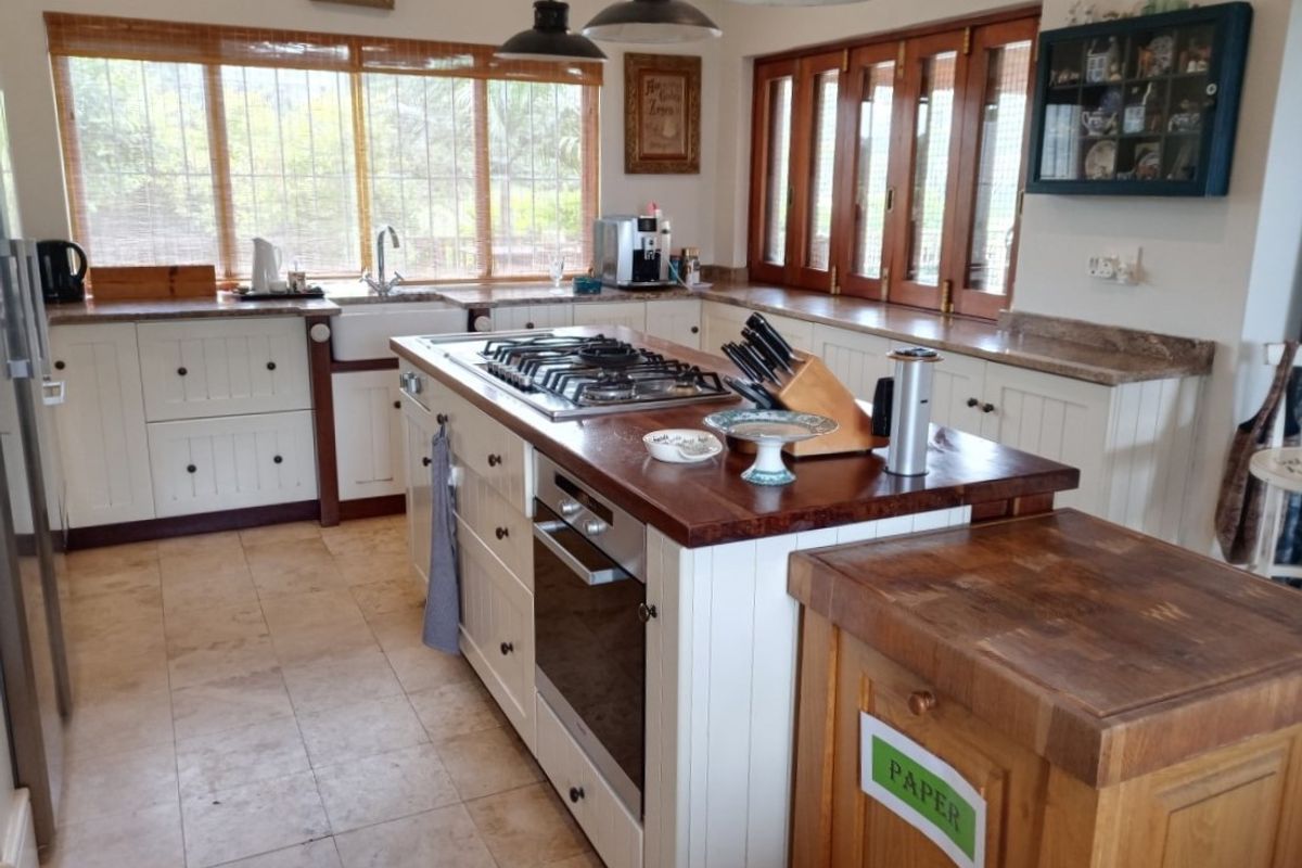A spacious country-style kitchen featuring a large central island with a built-in gas hob and oven, farmhouse sink, and ample wooden cabinetry.