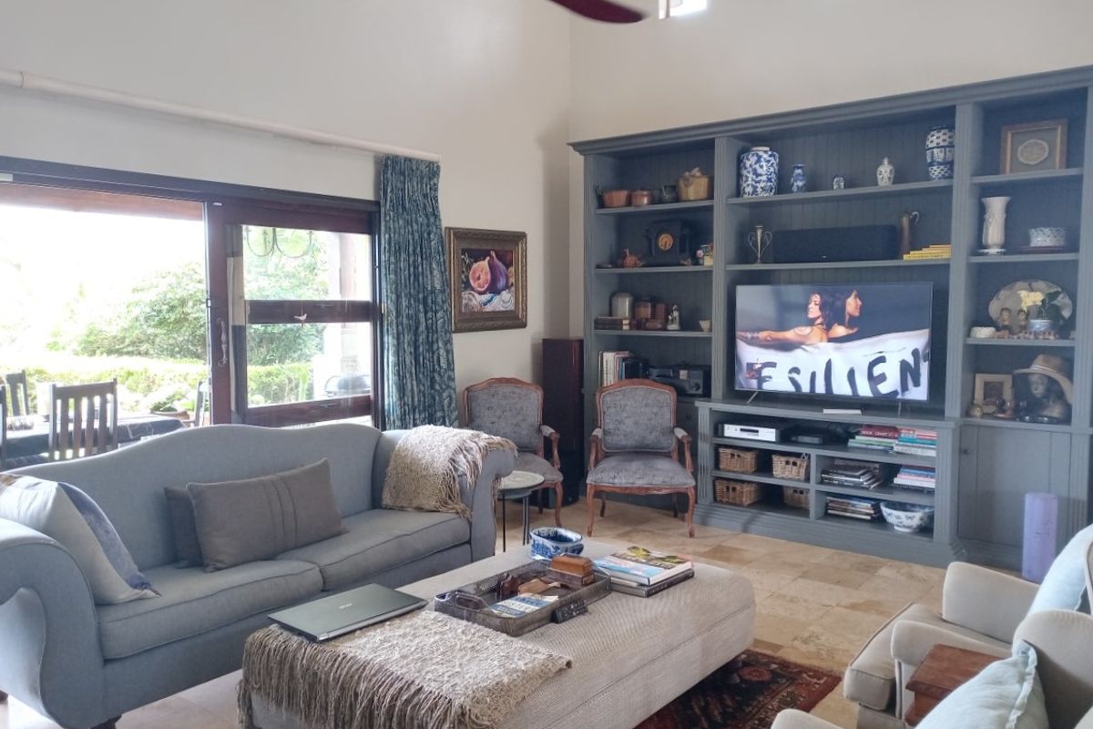 Spacious living room featuring high ceilings, a large built-in grey cabinetry unit, stone flooring, and sliding glass doors leading to an outdoor area.