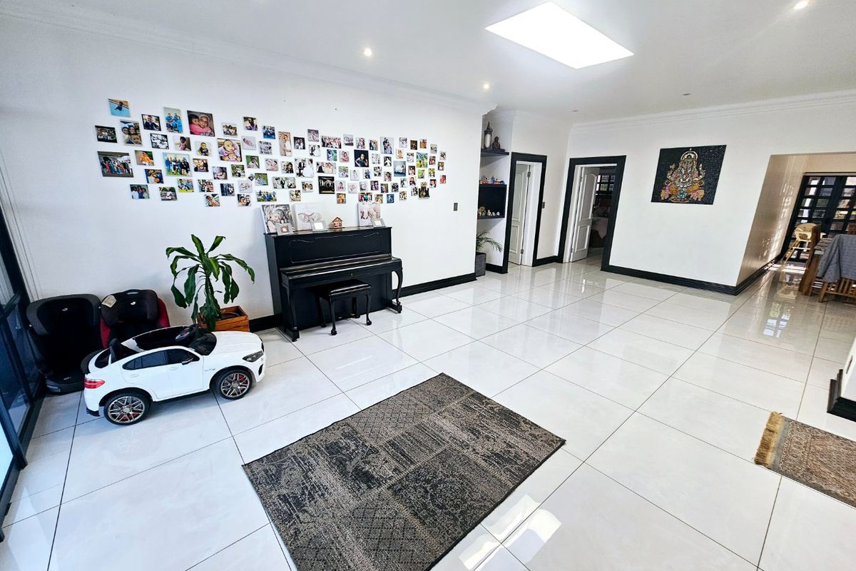 Spacious living area featuring large format white porcelain floor tiles, recessed downlighting, and a skylight, creating a bright and open atmosphere.
