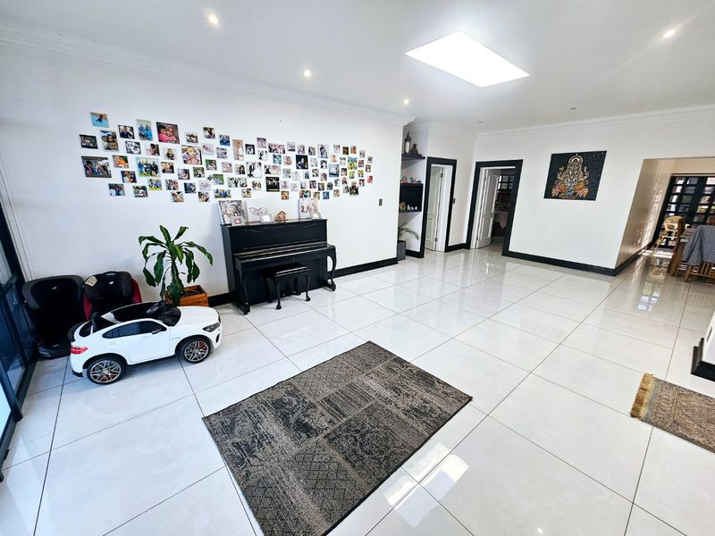 Spacious living area featuring large format white porcelain floor tiles, recessed downlighting, and a skylight, creating a bright and open atmosphere.