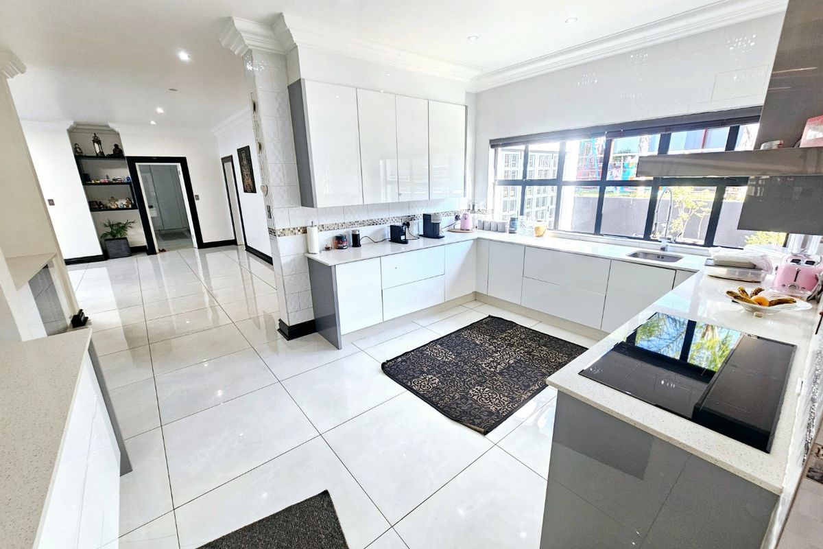 Modern kitchen featuring glossy white cabinetry, stone countertops, integrated induction hob, and large porcelain floor tiles with an open-plan layout.
