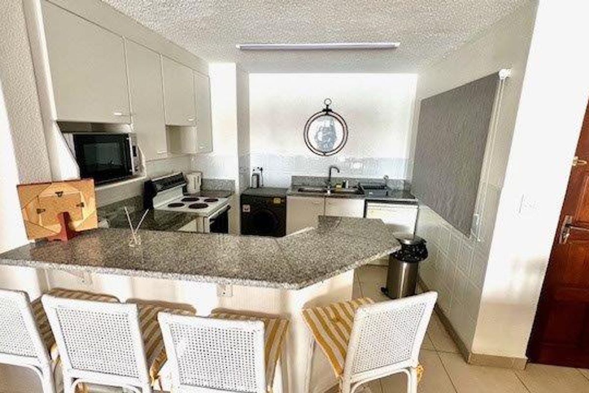 A functional kitchen featuring granite countertops, built-in cabinetry, an electric stove, and a breakfast bar, providing a practical layout for daily use.