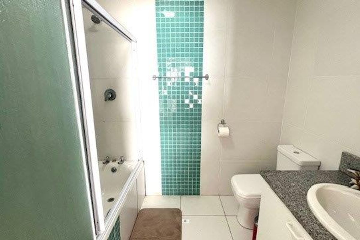 A functional bathroom featuring a shower-over-bath combination, a mosaic tile accent wall, and a vanity with a stone countertop.