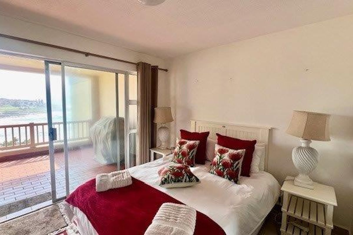 A bedroom featuring direct access to a private balcony with scenic coastal views through large sliding glass doors.